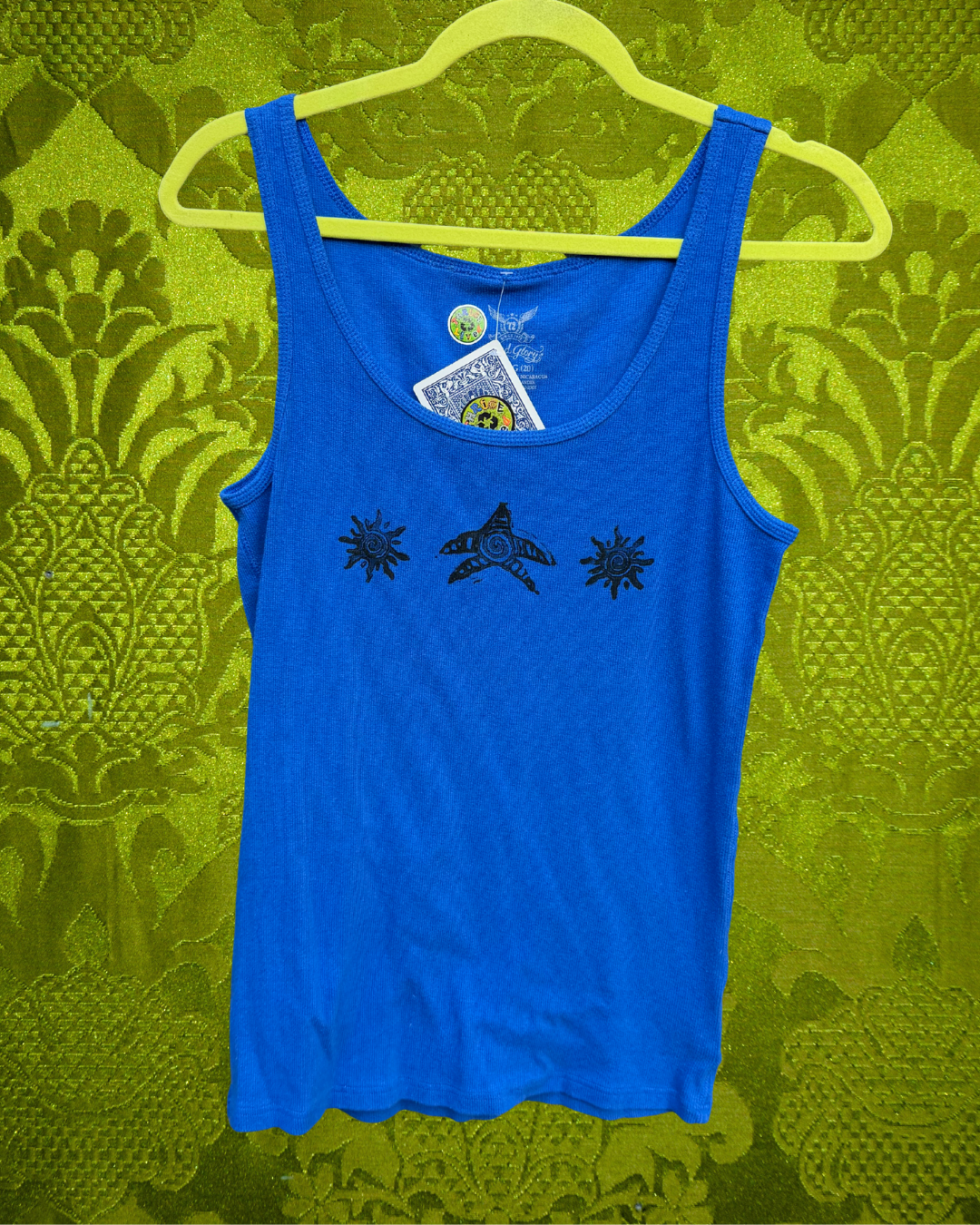 A vintage blue ribbed tank top with a black graphic print of two suns and a star in the middle on the front, with a green damask background.