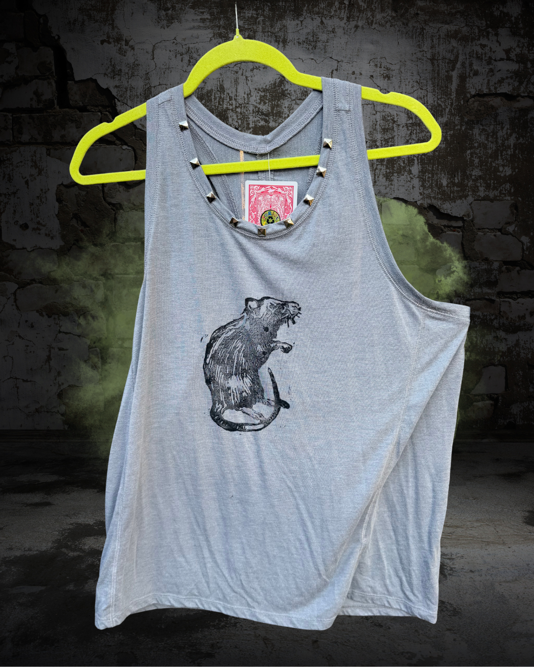 A light grey sleeveless tank top featuring a pyramid studded neckline and a black hand printed graphic of a rat on the chest. 